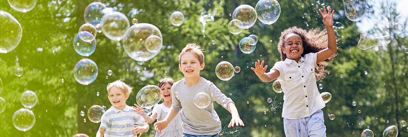 Group of kids running outdoors through bubbles